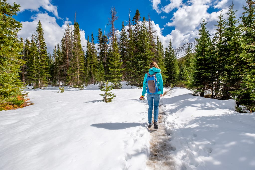 Tourist with backpack hiking on snowy trail hiking in the snow
