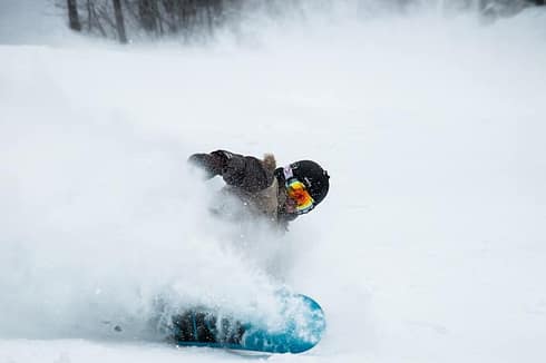 photo-1488580923008-6f98dfbd7a25 A snowboarder wearing goggles and winter gear kicks up a spray of snow while making a sharp turn on a snowy slope in Verbier, surrounded by a stunning winter landscape perfect for skiing and travel adventures. David Pearson Travel